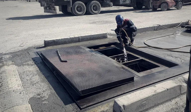 Technicien SCALMAR nettoyant la fosse d'un pont-bascule en exploitation
